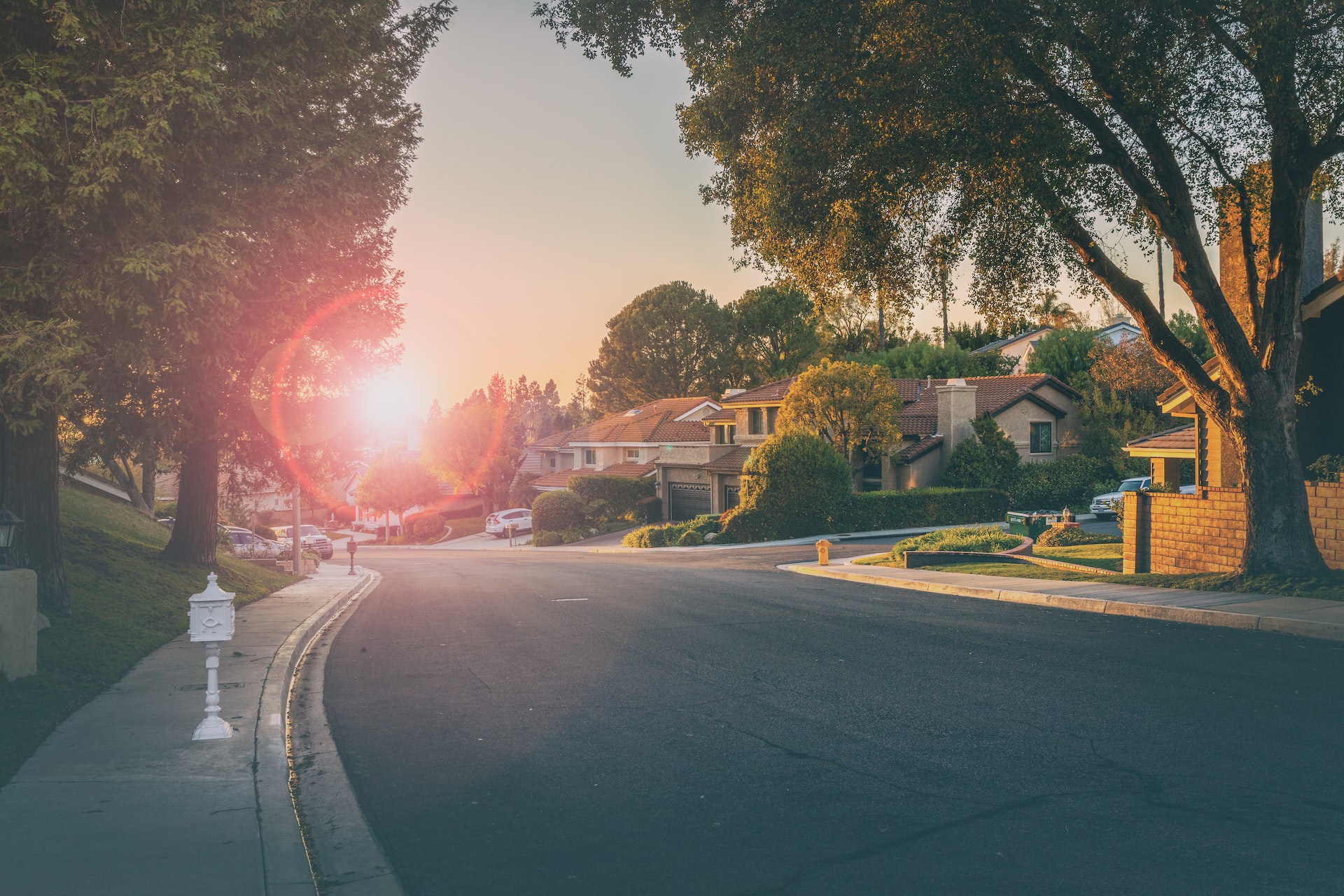View of a residential street lined with houses at sunset, representing real estate deals and Certificates of Pending Litigation